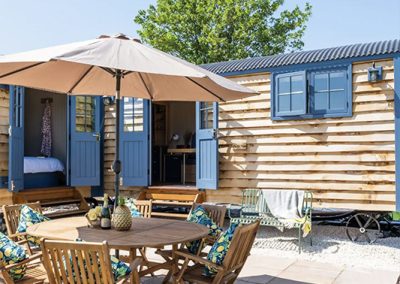 Outdoor furniture and a parasol outside the shepherds hut